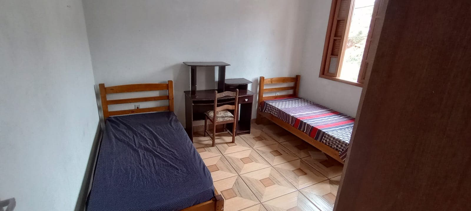 Quarto duplo com mesas de estudo e armários.